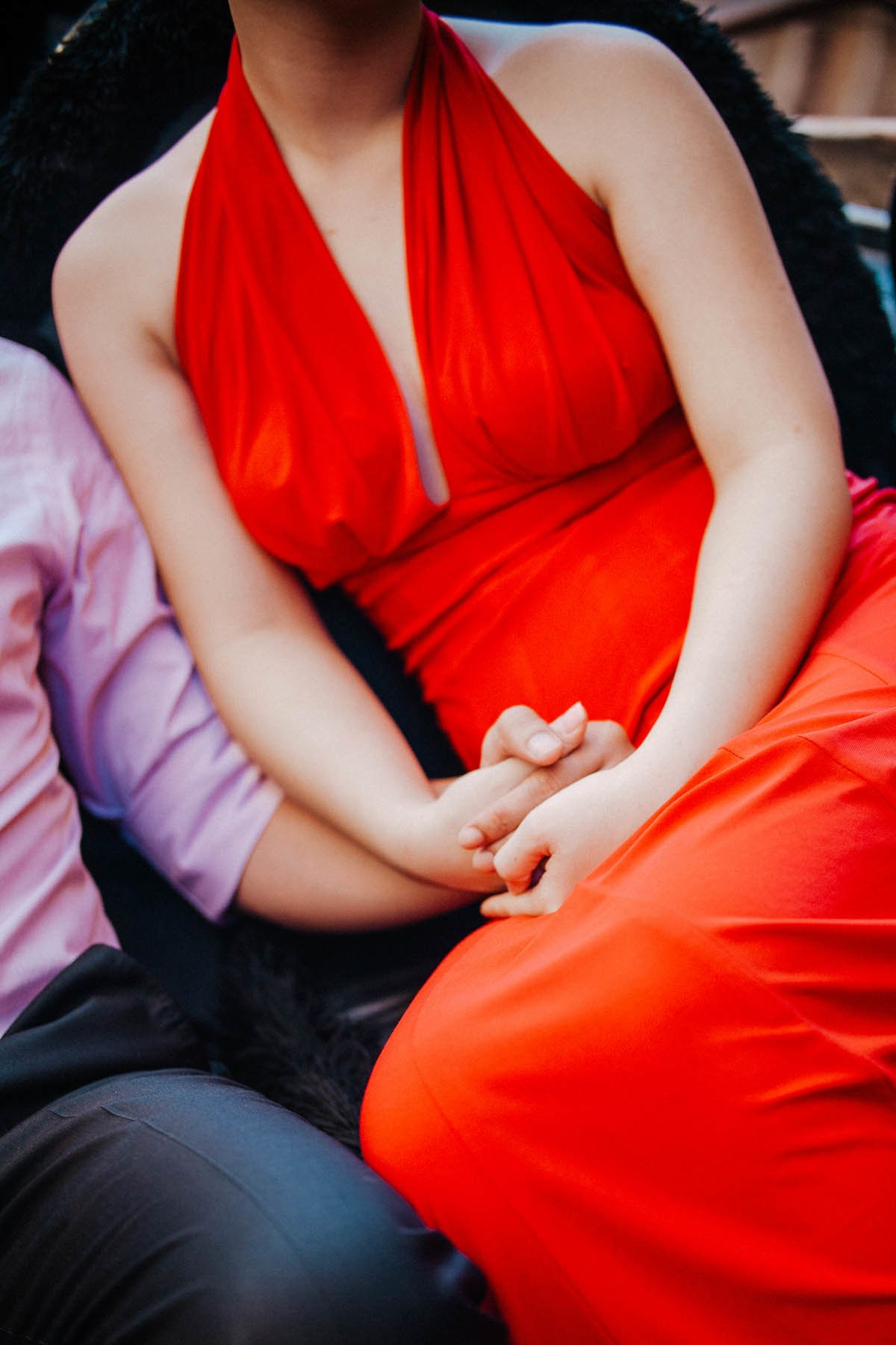 Man and woman in skin-tight dress holding hands sitting in gondola Venice.