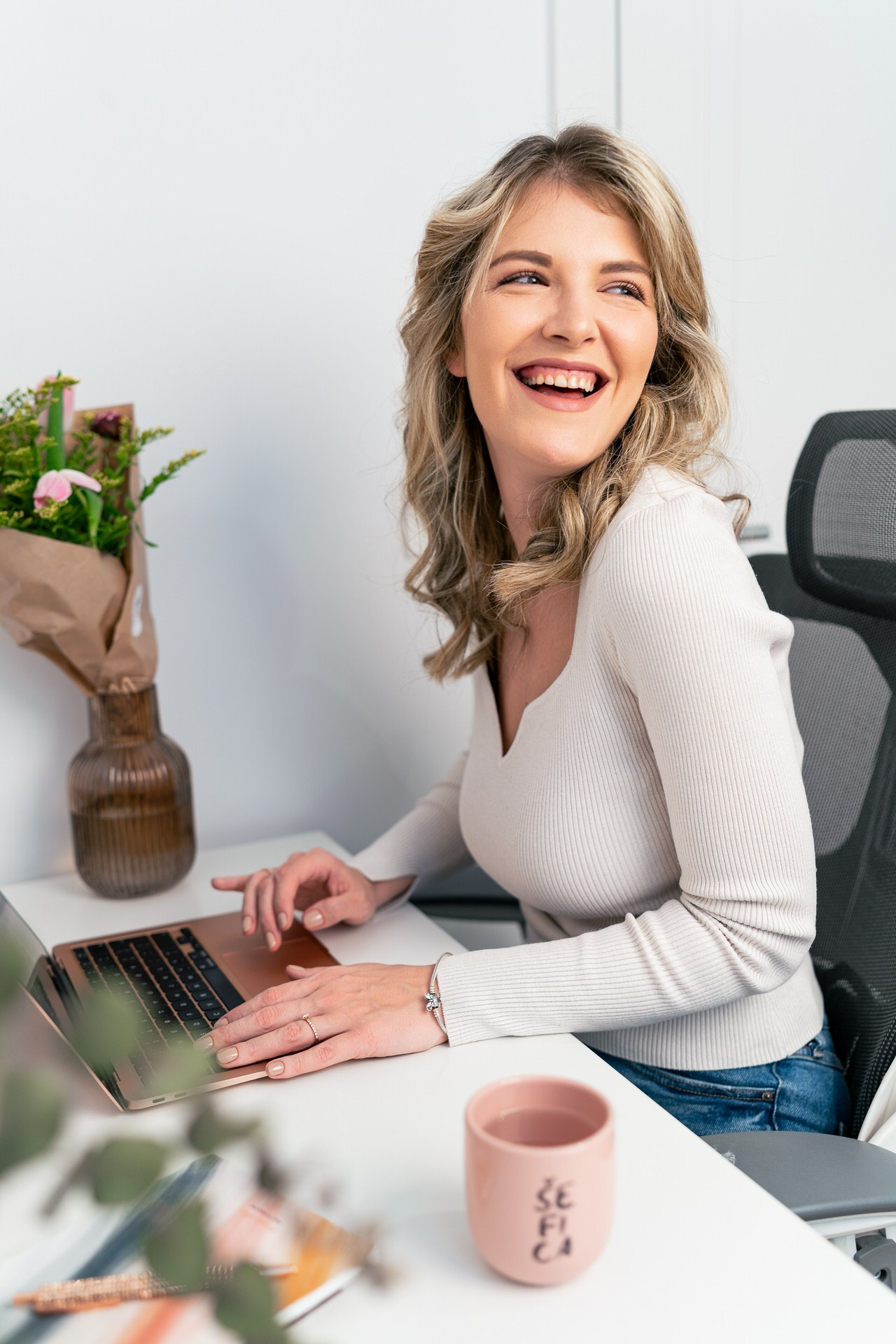 iskren osmeh mlade preduzetnice u radnom okruženju za laptopom