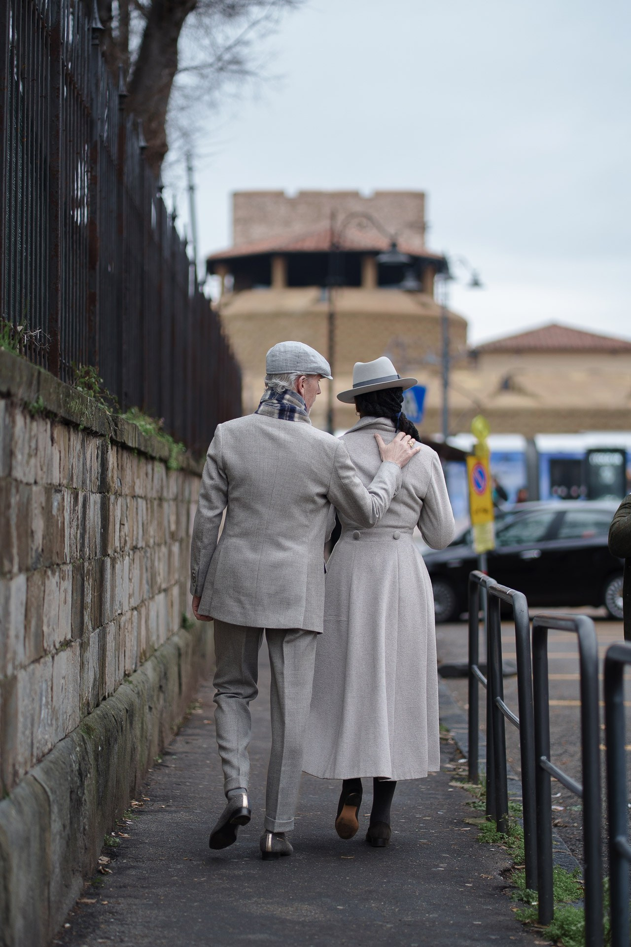 Elegant couple in grey outfits walking together near Pitti Uomo 109 Florence