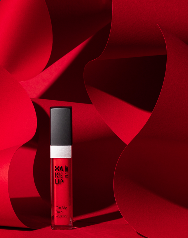 Red lipstick surrounded by folded paper shapes — bold luxury cosmetic photography.