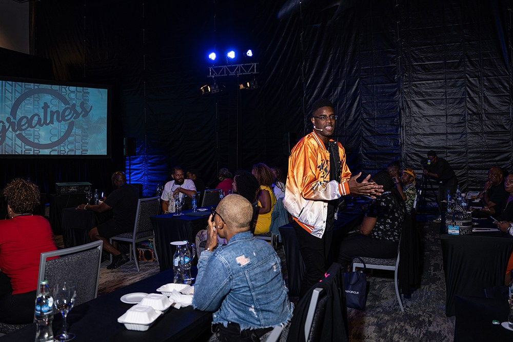 Speaker pointing at screen while audience watches presentation.