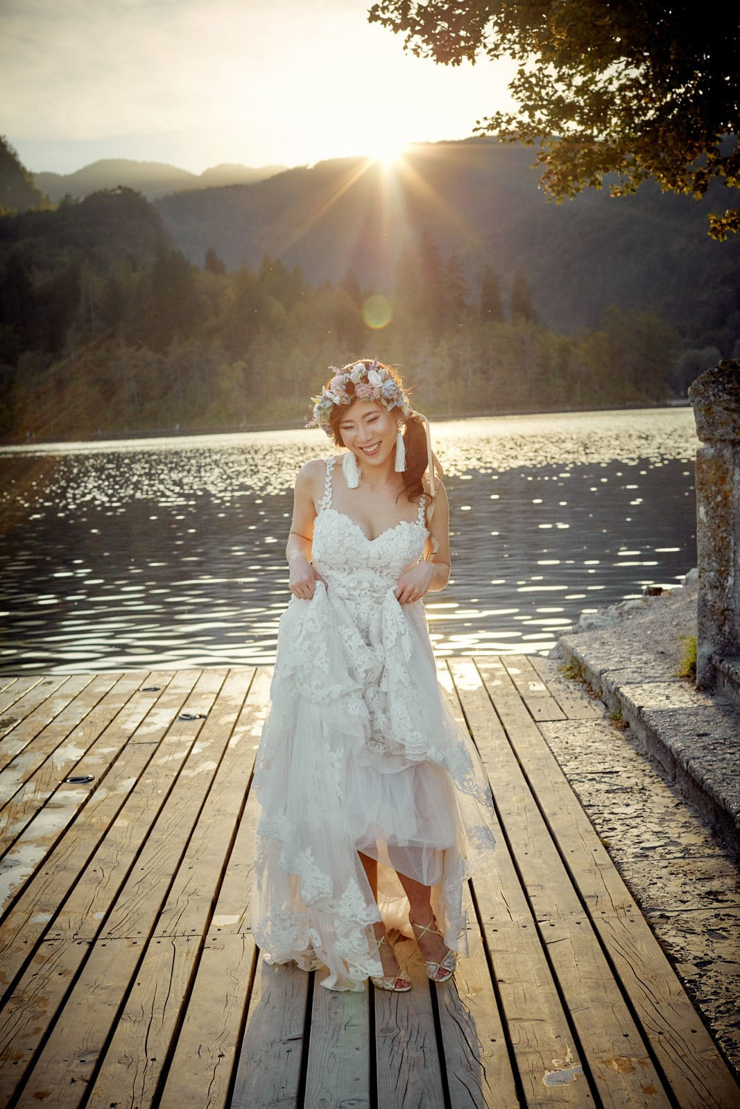 Radiant bride walking toward pletna boat golden hour Lake Bled.