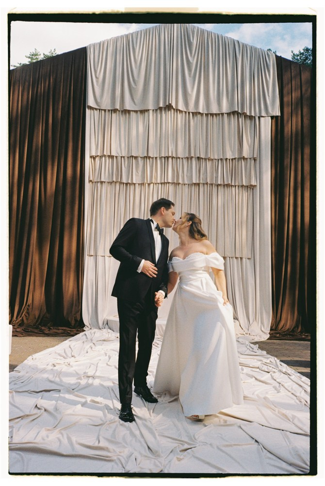 Couple standing before draped backdrop during wedding portraits