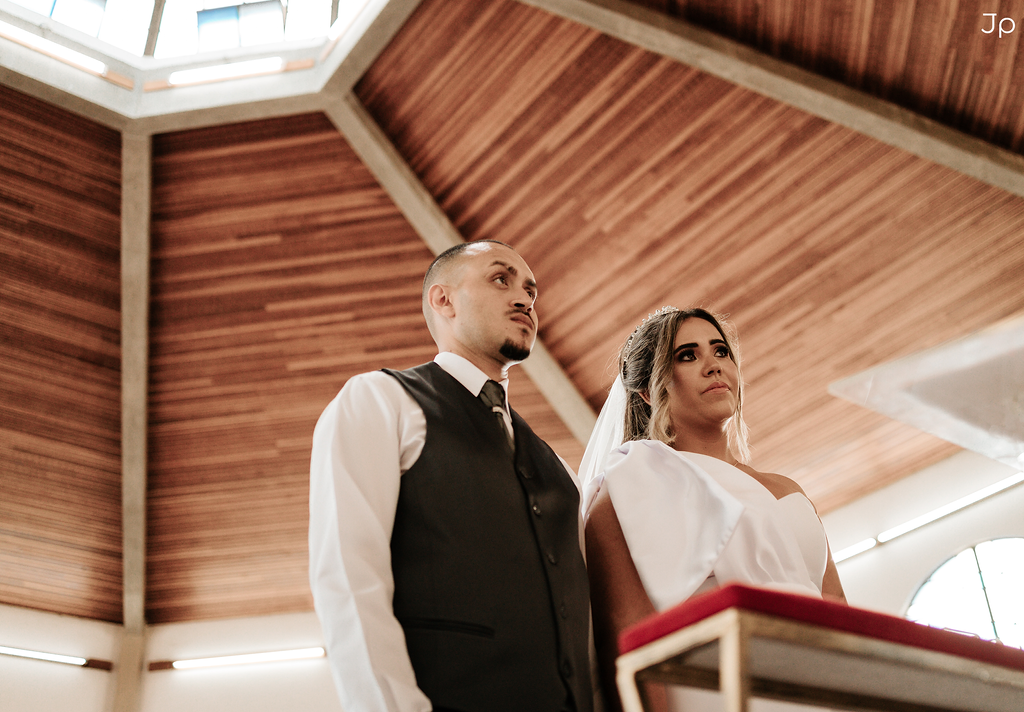 Casal no altar ouvindo o celebrante com atenção.