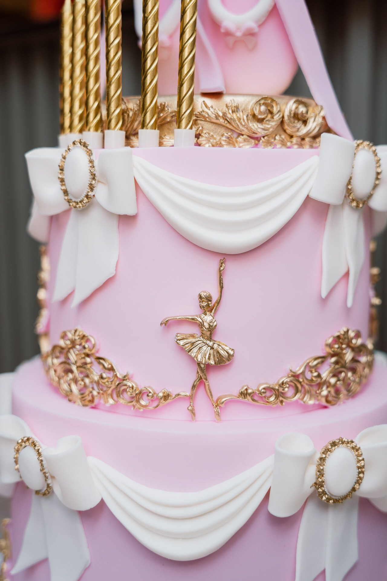 Fotografija raskošne rođendanske torte sa više spratova ukrašene zlatnim detaljima.