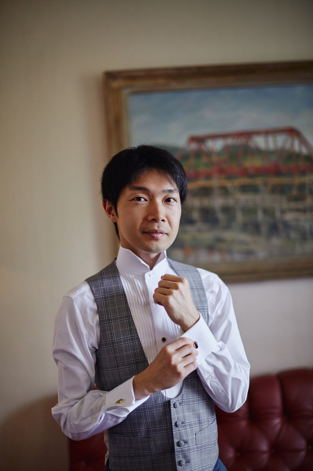 Groom adjusts his cuff links as he looks into the camera.