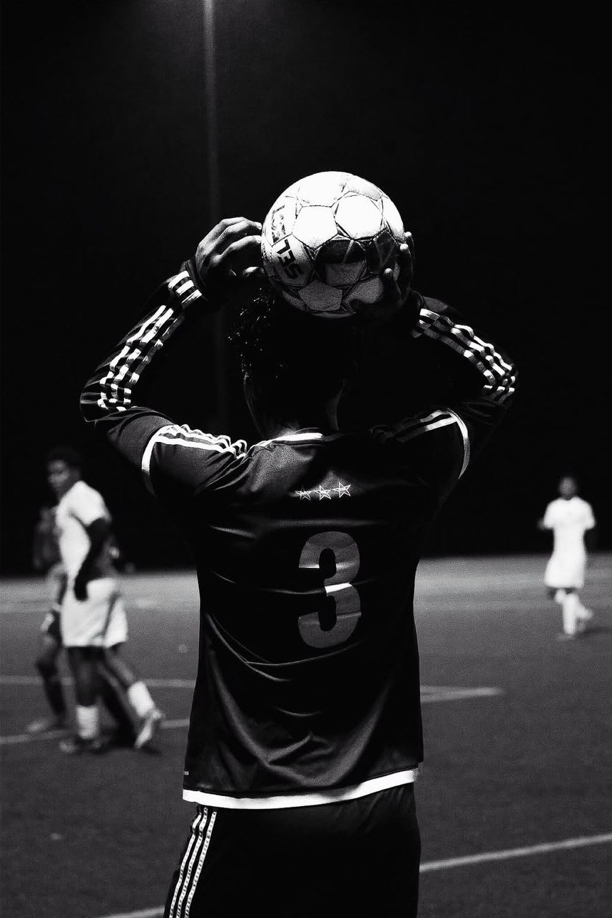 Black and white portrait of a soccer player standing with the ball in his hand, ready to throw. lowered in a quiet, focused moment.
