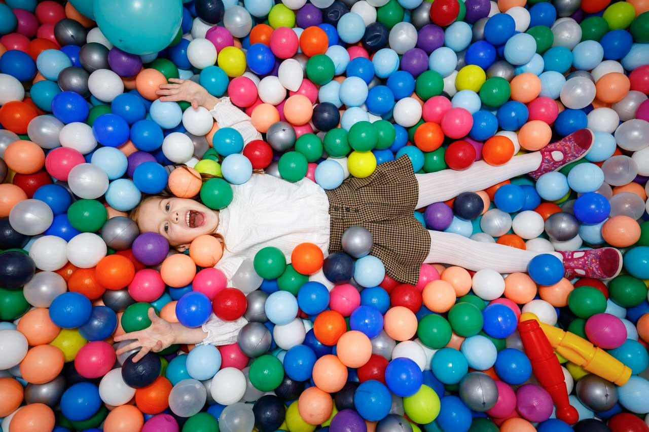 Slavljenica u bazenu od šarenih lopti na proslavi rođendana u igraonici.