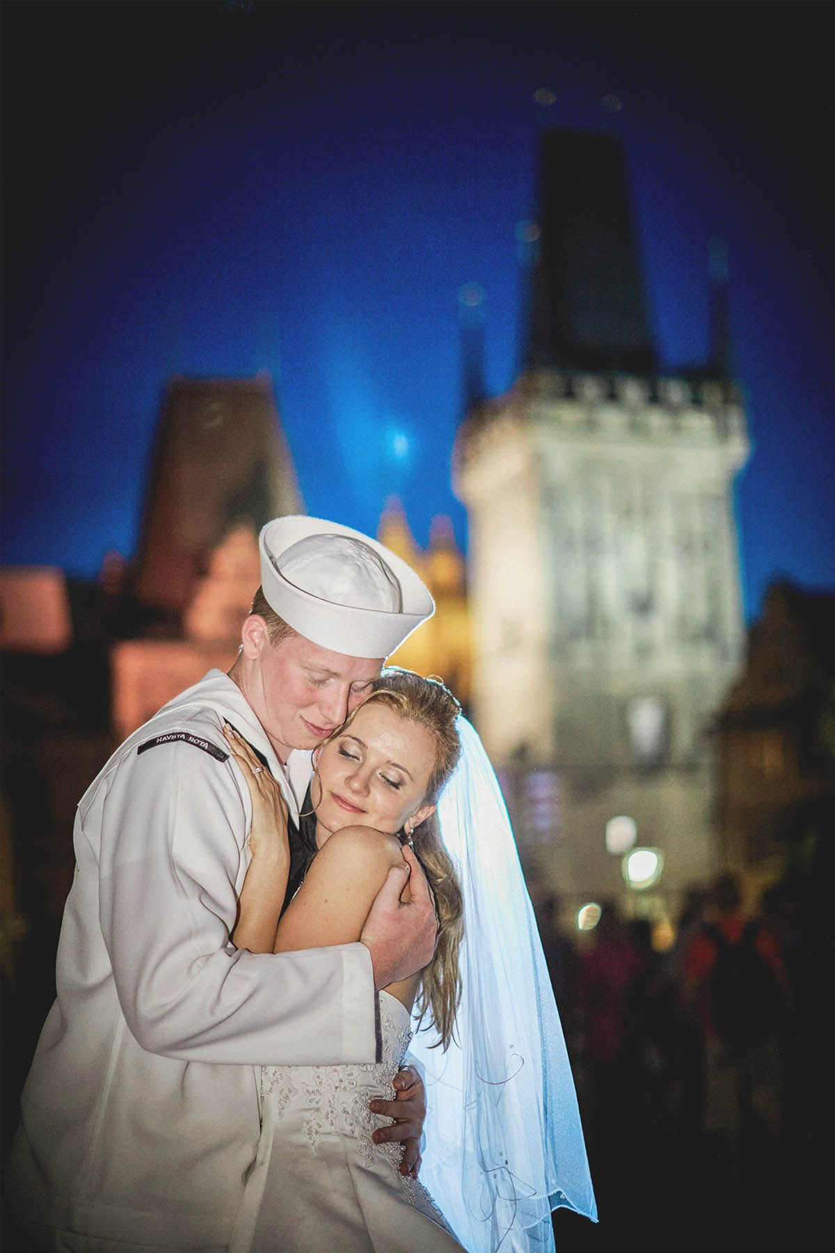 Naval officer embracing bride on Charles Bridge at night, Prague wedding