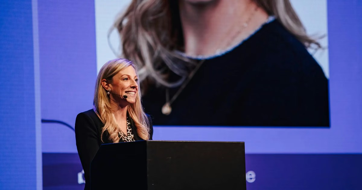 Female speaker presenting from a lectern at an industry event