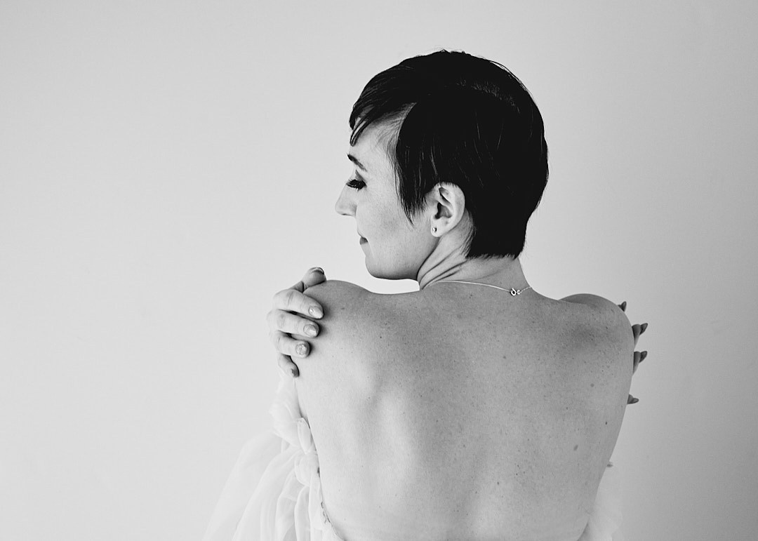 topless woman from behind hugging herself 