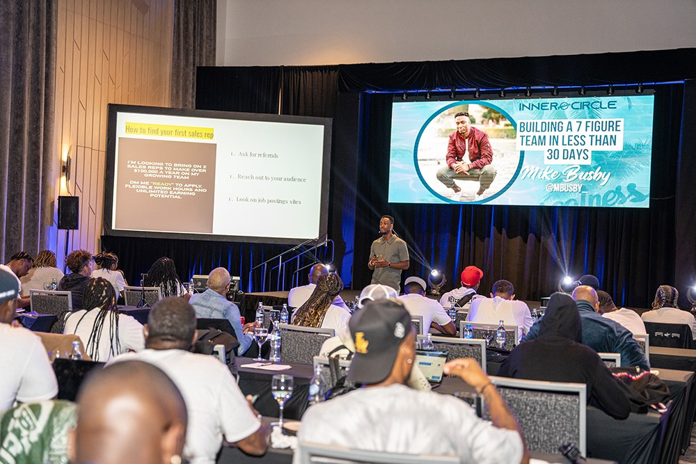 Speaker presenting on stage while audience listens attentively.