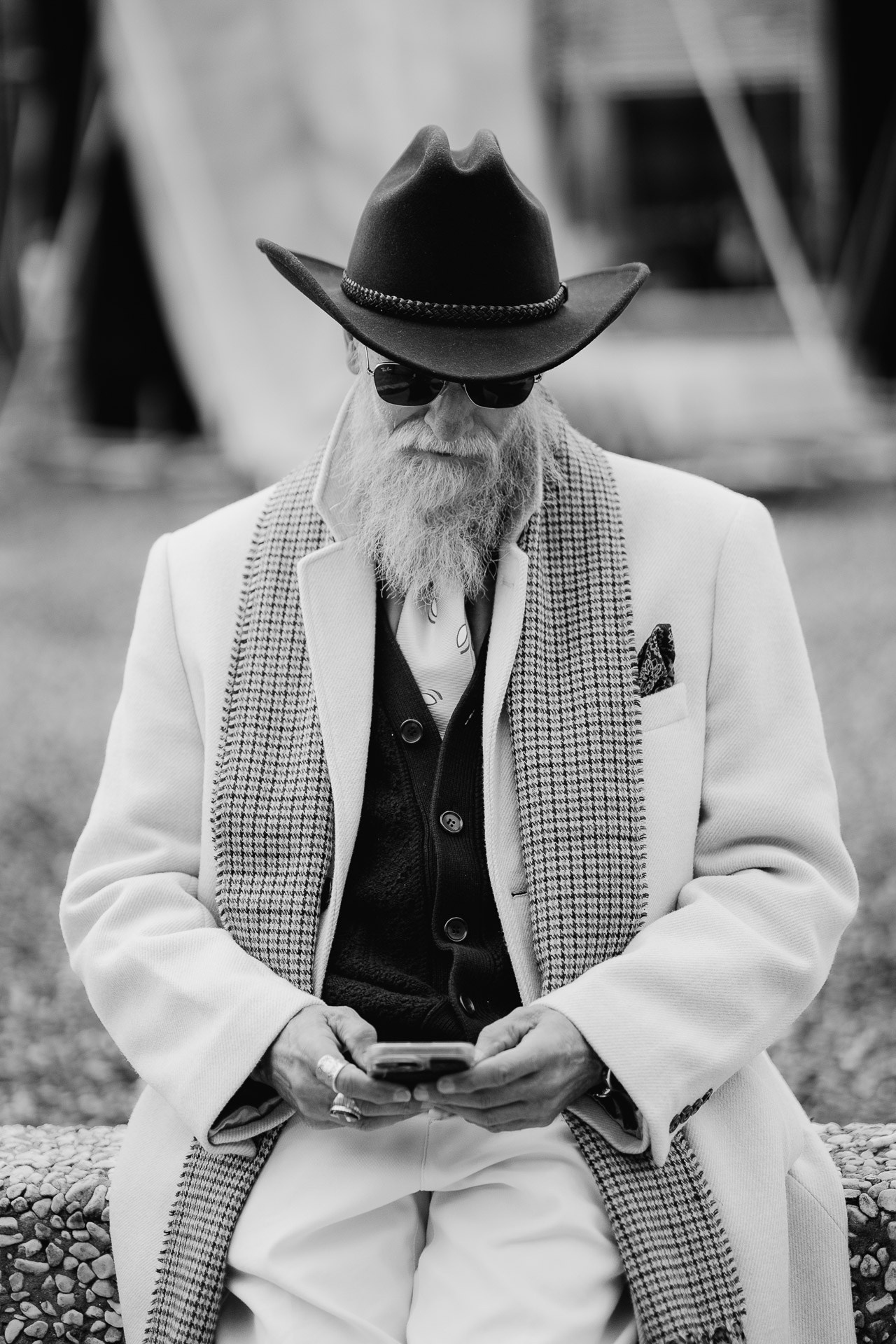 Black and white portrait of bearded man in white coat and hat at Pitti Uomo