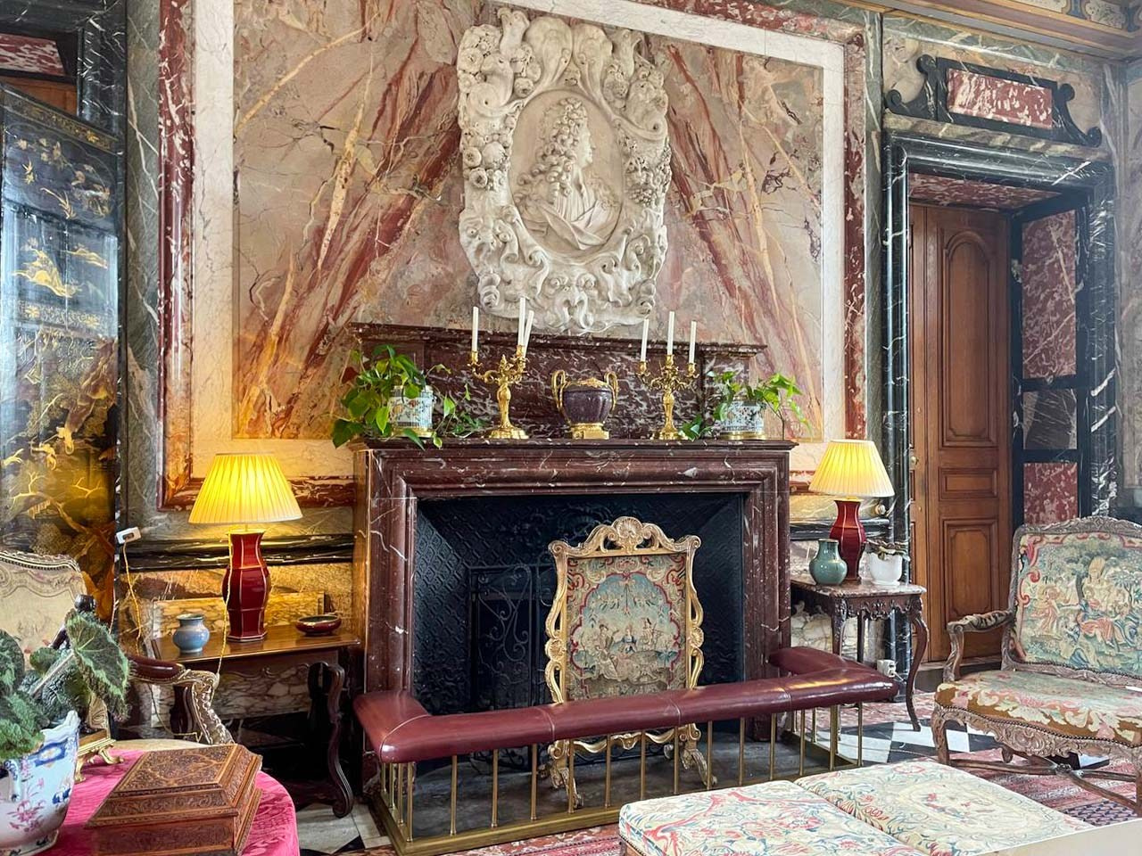 Historic marble fireplace and antique furnishings inside Château de Courances, showcasing elegant French aristocratic interior design