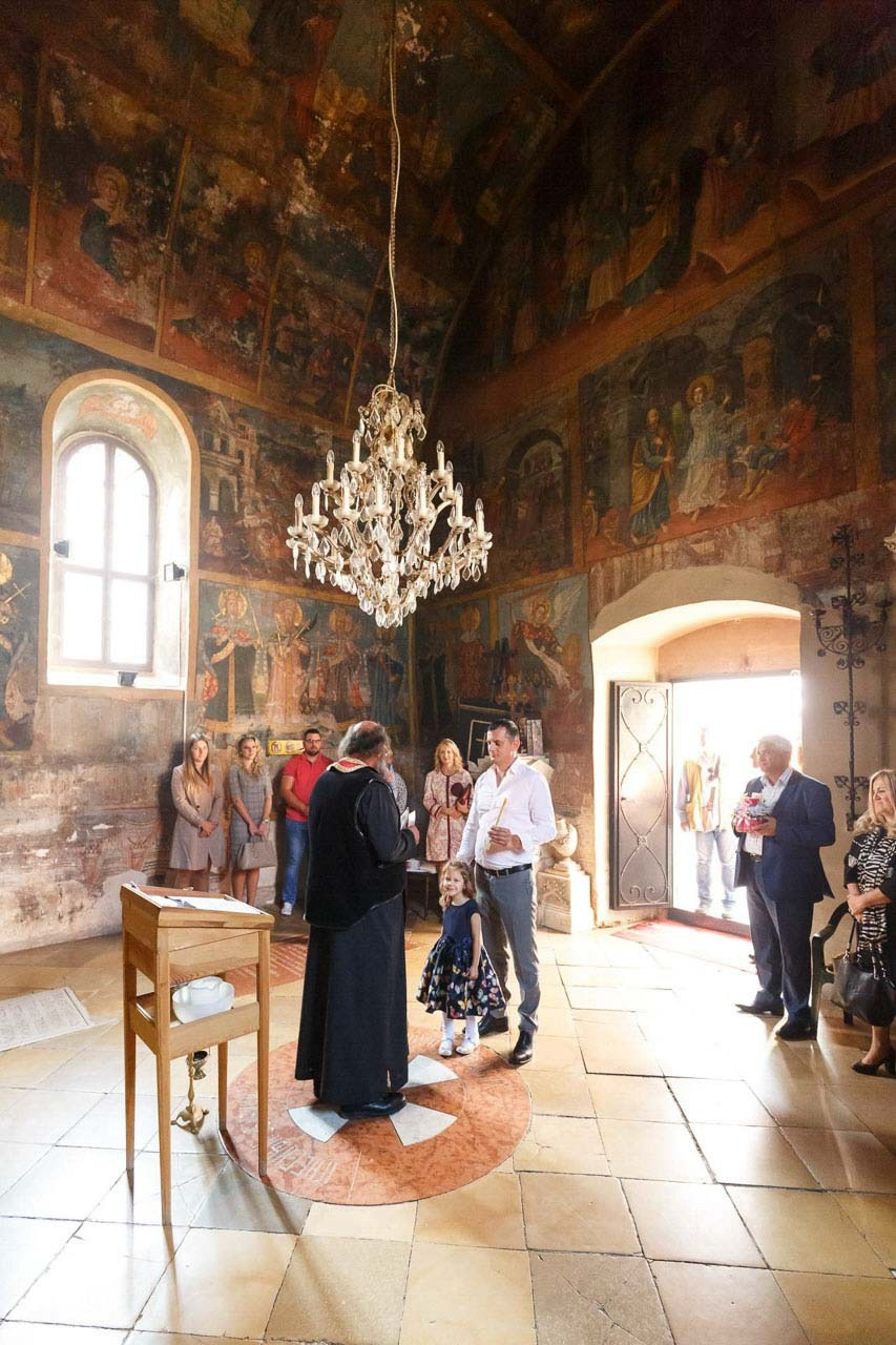 Svečano okruženje u crkvi sa porodicom i prijateljima tokom krštenja.