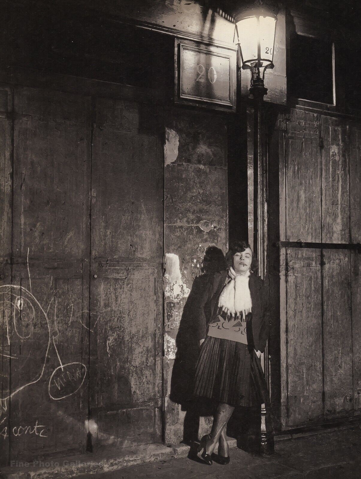 Фотография Брассая «Женщина-проститутка, Париж ночью»: женщина стоит одна на тёмной улице под светом фонаря, в пальто и шляпе, олицетворяя атмосферу ночного Парижа 1930-х годов.