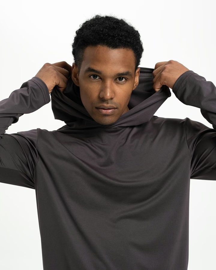 Close-up fashion shot of a model lifting the hood of a sleek sportswear top