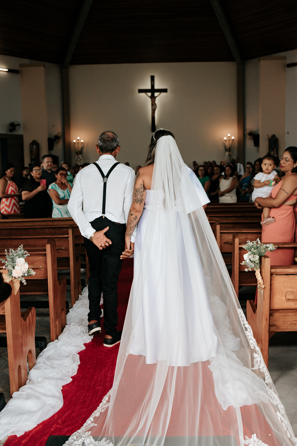 Noiva desfilando pelo tapete vermelho até o altar, momento clássico e marcante do casamento.