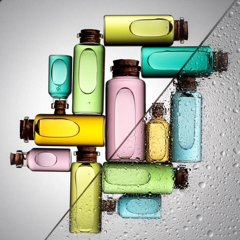 Vibrant multicoloured glass bottles layout — editorial product flatlay for fragrance campaign.