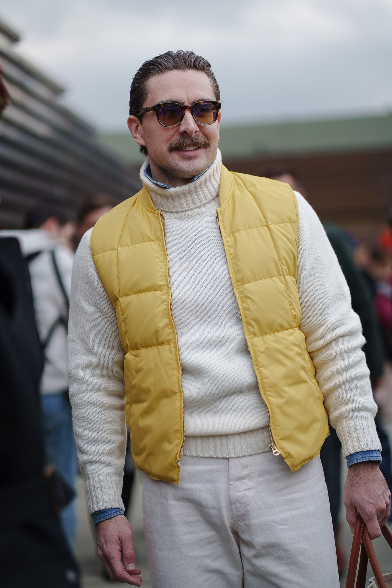 Man in yellow vest over white sweater walking at Pitti Uomo 109 Florence