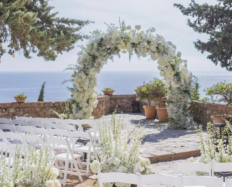 Wedding arch and white chairs with flowers sea view