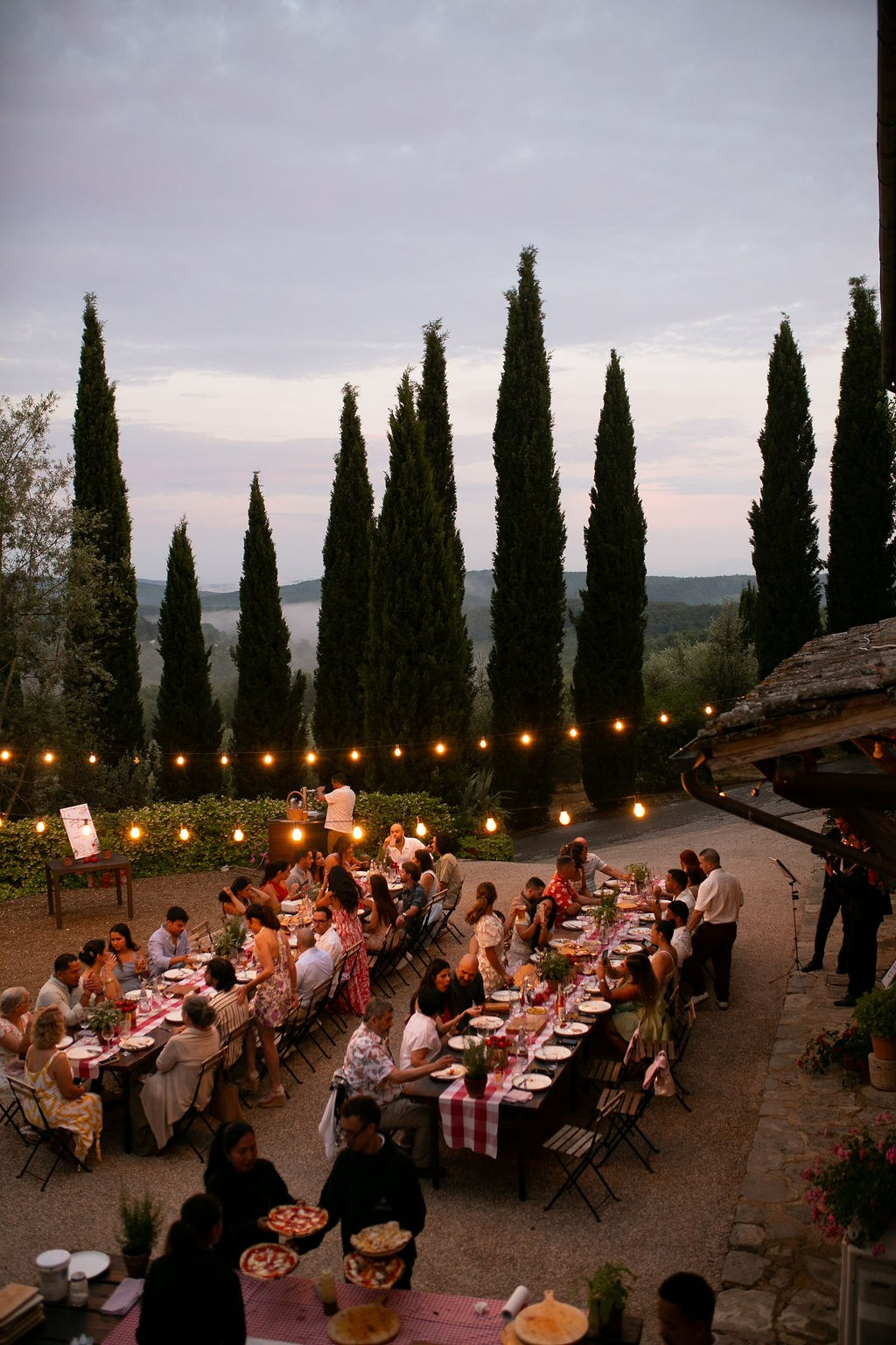 Outdoor wedding reception in Tuscany with guests celebrating at sunset
