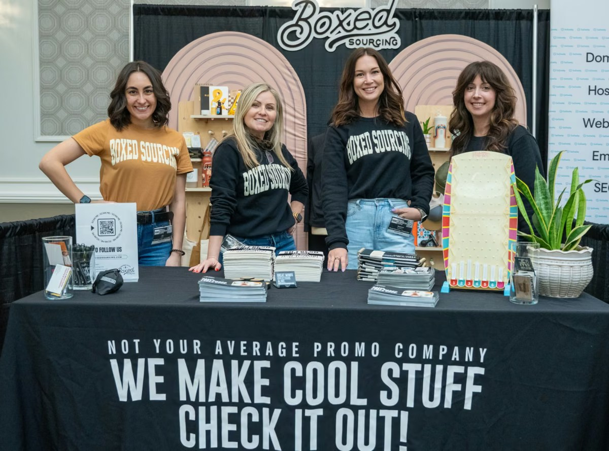 Four female exhibitors welcoming visitors at a branded trade show stand
