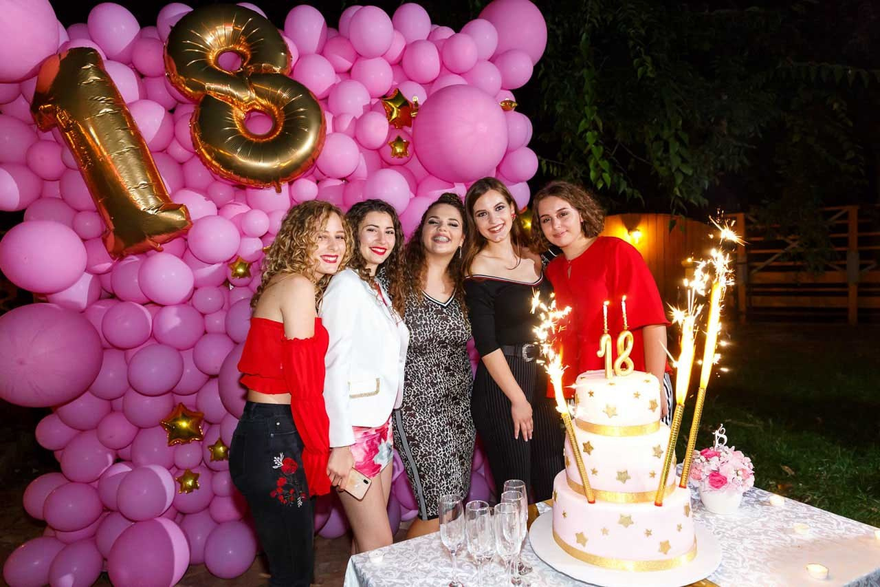 Slavljenica sa porodicom i prijateljima pored torte na 18. rođendanu.