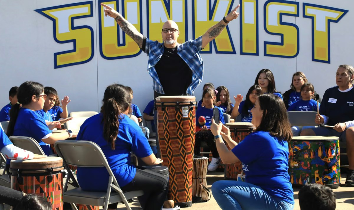 Youth percussion group performing on stage at a community event