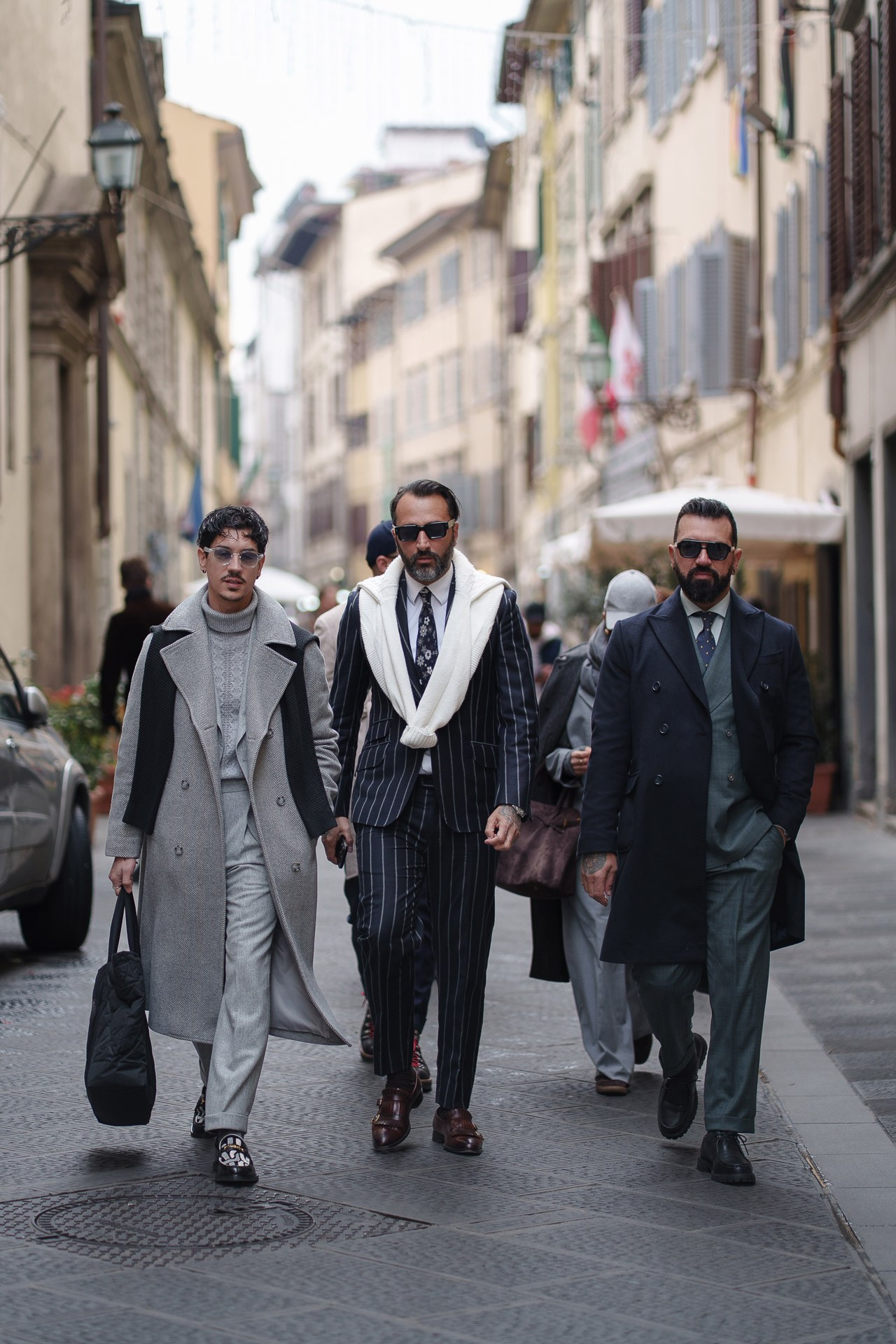 Elegant group of men in classic menswear walking together at Pitti Uomo 109 Florence