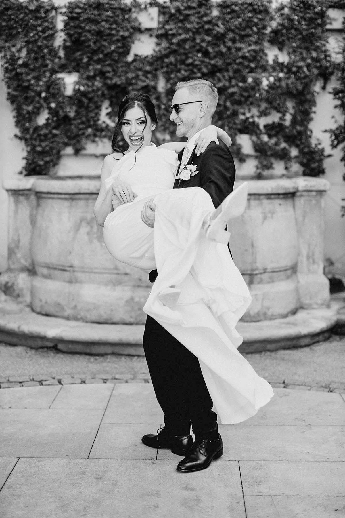 Happy bride laughs as she is spun around by her blonde-haired Czech groom wearing Ray-Ban sunglasses.