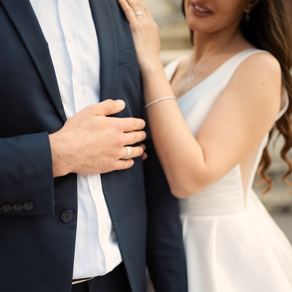 Mladoženja u sakou sa zlatnom burmom i mlada pored njega.