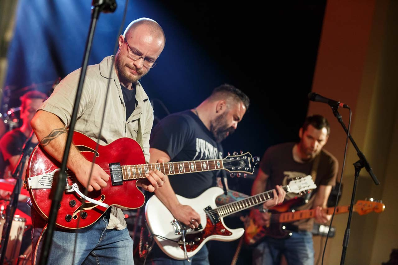 Zajednički nastup trojice muzičara Moonshine Alligators benda sa električnim gitarama na koncertu.