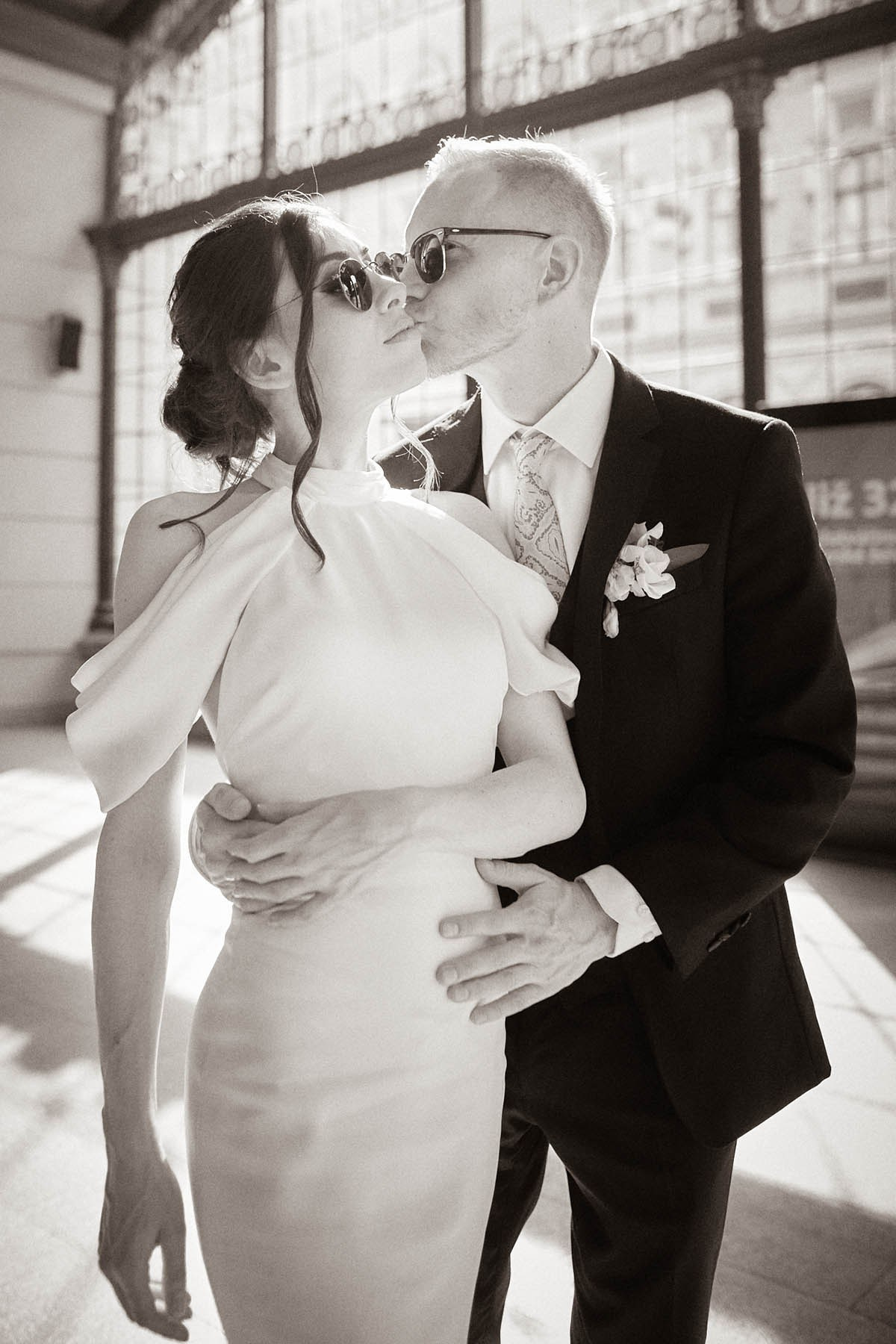 Bride and groom stealing a quiet kiss during their wedding day escape at Praha-Masarykovo Station, Prague