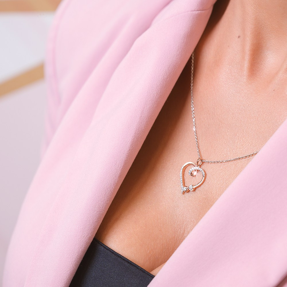 Zlatna ogrlica sa priveskom srca na modelu.