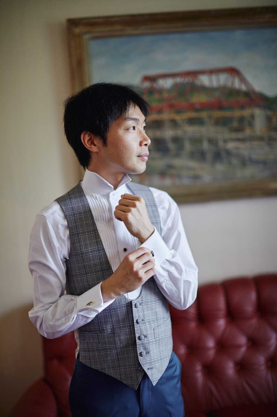 Japanese groom adjusting cufflinks window view Vila Bled suite.