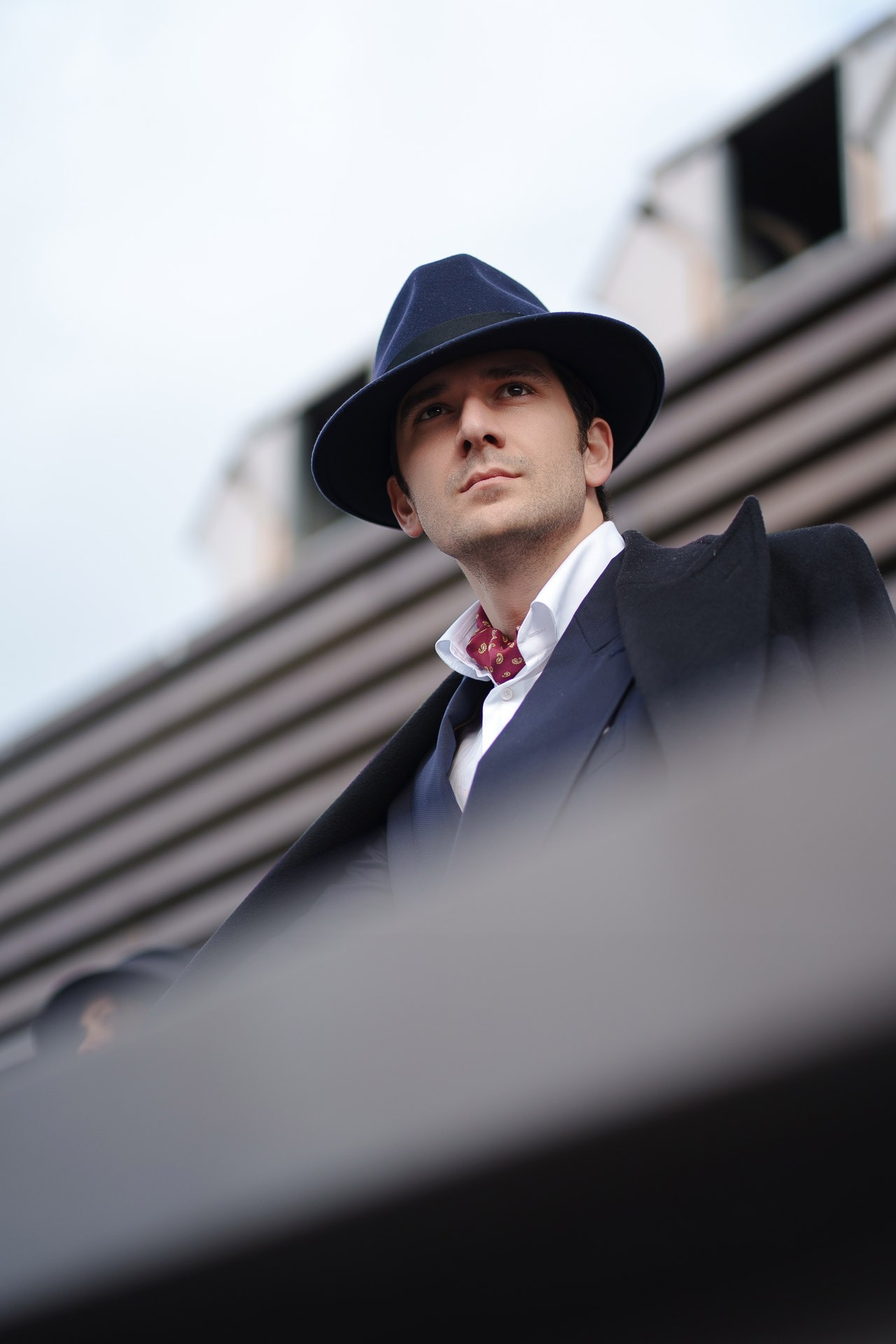 Man in dark coat and fedora hat looking up at Pitti Uomo 109 Florence