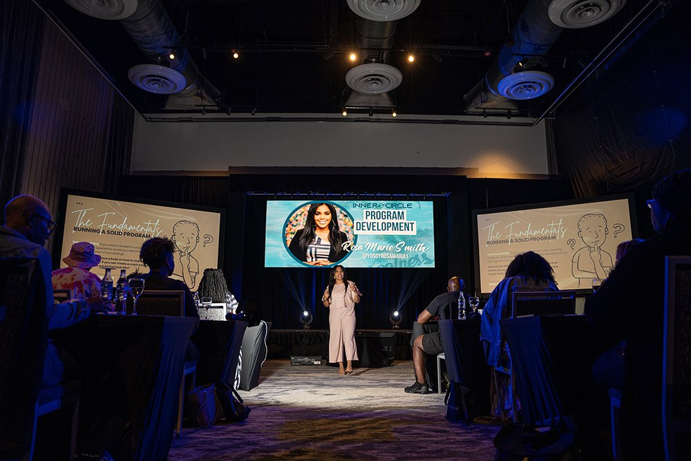 Event presenter discussing strategy while listeners take notes.
