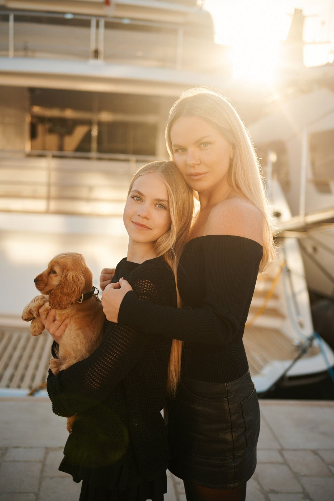 Candid outdoor shot of mother, daughter and puppy by luxury boats in Cannes