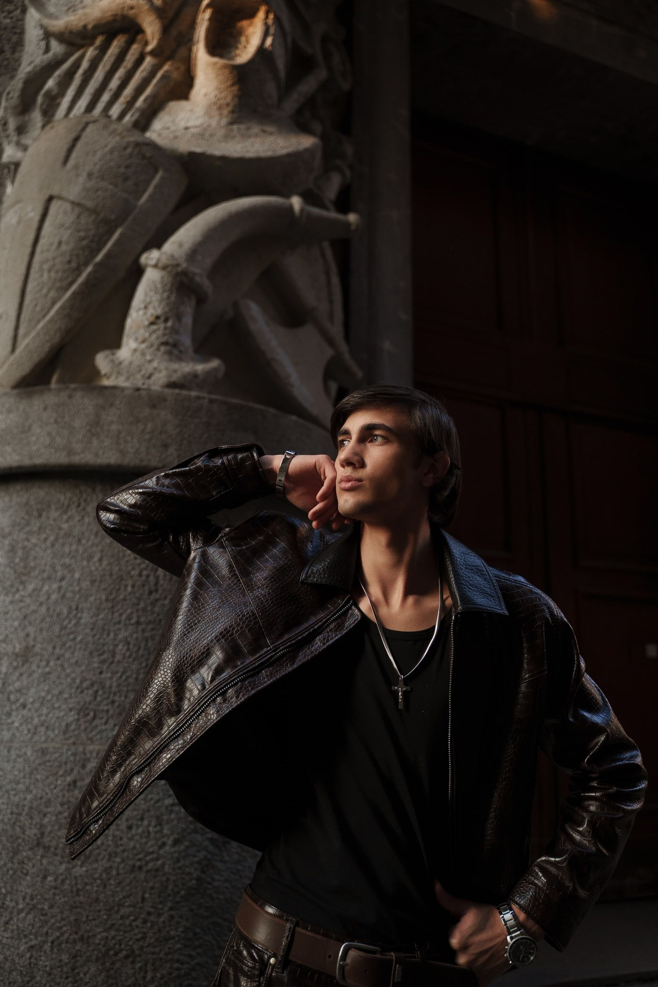 Male model posing by bronze pillar at architectural location in Milan