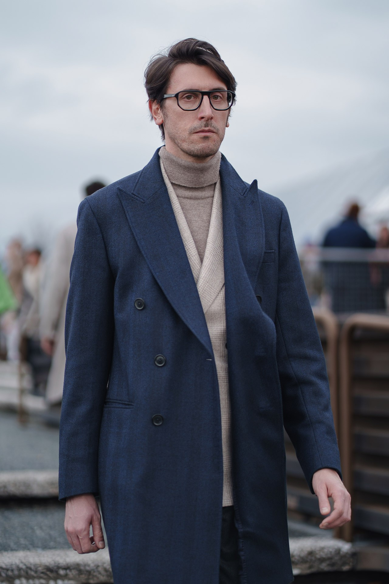 Man in navy overcoat and turtleneck posing at Pitti Uomo Florence