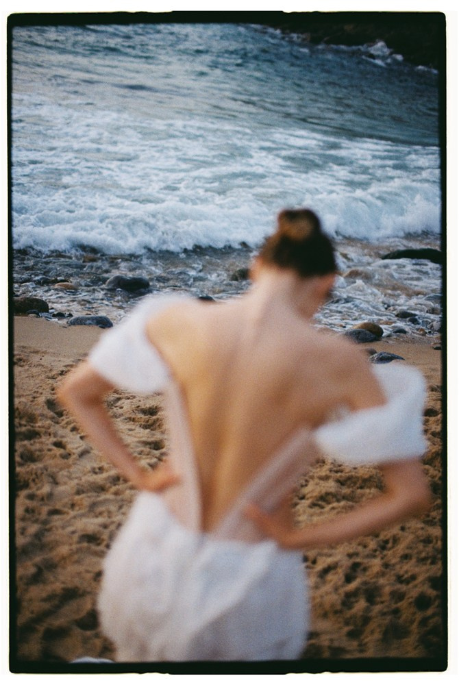 Bride adjusting dress by sea during Portugal destination wedding portraits