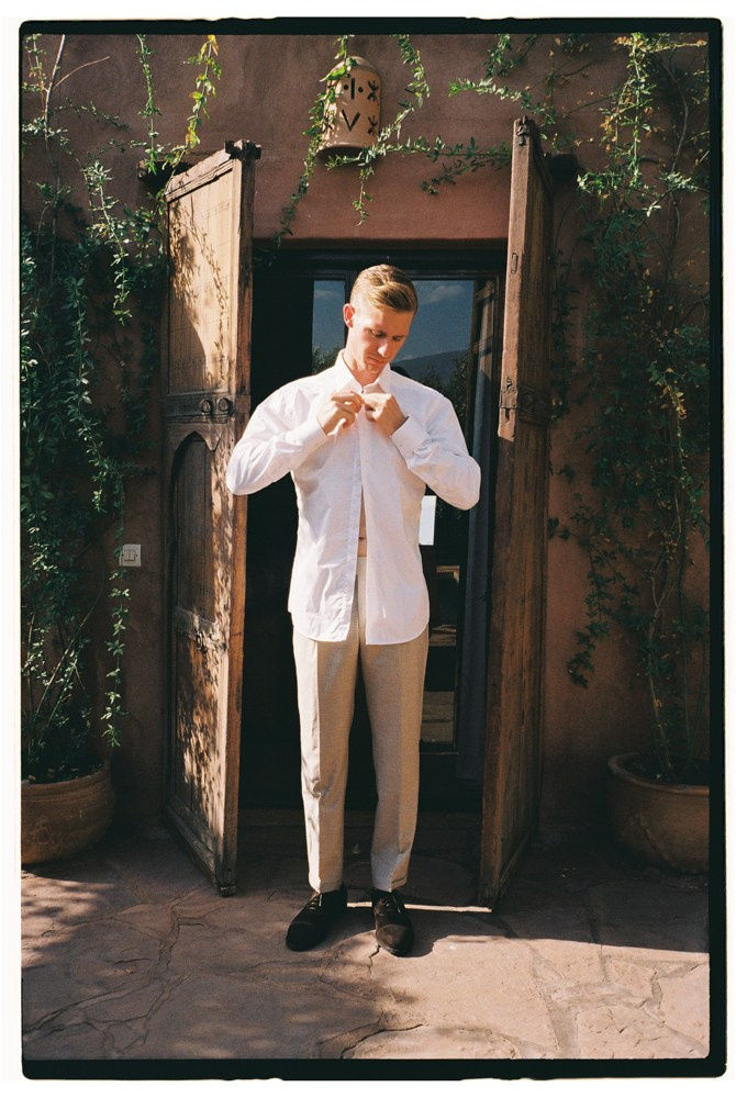 Groom adjusting shirt in doorway before Morocco wedding preparation