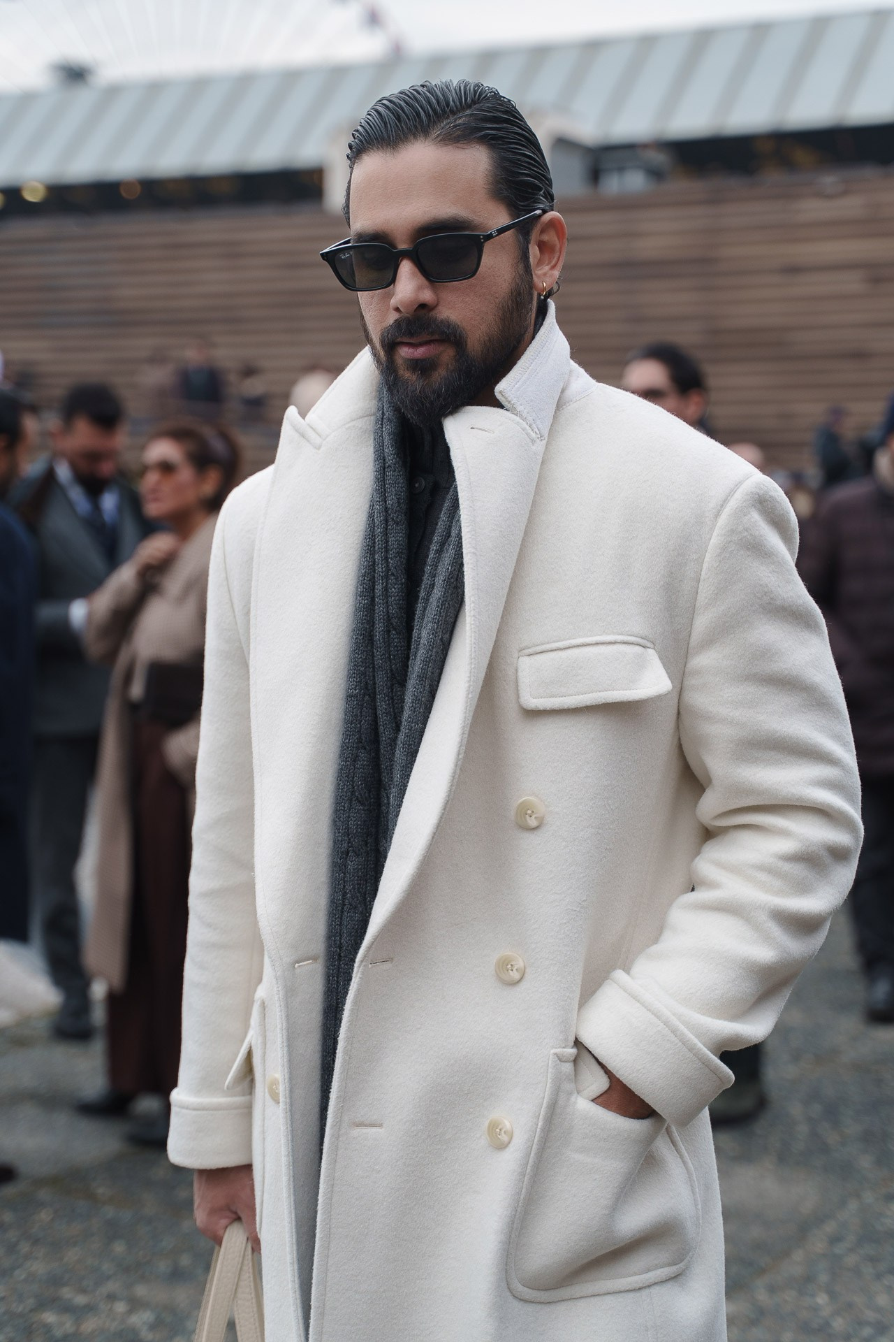 Man in white coat and scarf outside Pitti Uomo Florence street style