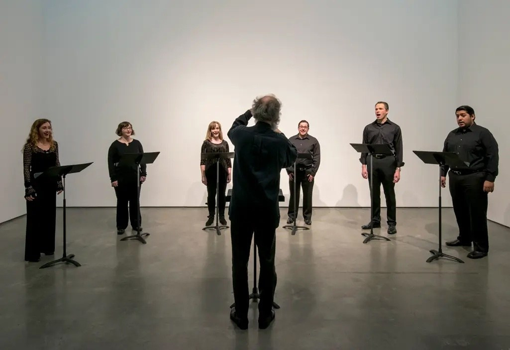 Перформанс «DOUG» (2014) Дженис Кербел, девятичастная музыкальная композиция для шести голосов, исполненная в Jeffrey Room, Mitchell Library, Глазго, представляет анти-дизайн через минималистичную, грубую эстетику, рассказывая о череде катастрофических событий, постигших вымышленного персонажа Дага, с акцентом на концептуальную «визуальную правду» и критику повествовательной формы. «DOUG» (2014) — перформативная работа канадской художницы Дженис Кербел (Janice Kerbel, род. 1969, Торонто, живёт в Лондоне), созданная по заказу The Common Guild и впервые исполненная 1 мая 2014 года в Mitchell Library, Глазго. Это музыкальная композиция из девяти песен для шести голосов, рассказывающая о злоключениях вымышленного персонажа Дага, который переживает серию трагикомичных катастроф (например, нападение медведя, падение объекта с неба, удар молнии). Работа, номинированная на Turner Prize 2015, использует строгую музыкальную форму, но отвергает визуальную полированность, соответствуя эстетике анти-дизайна и брутализма. Кербел, не имея музыкального образования, работала с композиторами и программой нотации, чтобы создать партитуру, подчёркивая «сырую» природу перформанса. Отсутствие публичной записи усиливает эфемерность работы, акцентируя внимание на живом опыте. «DOUG» также сопровождался серией шелкографических отпечатков, использующих типографские элементы для визуального воплощения музыки, что демонстрирует интерес Кербел к переосмыслению языков и форм коммуникации. 