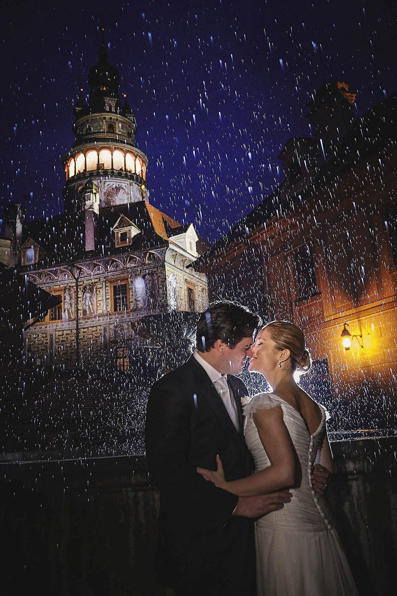 A couple kiss in the rain in the courtyard of Cesky Krumlov Castle at night