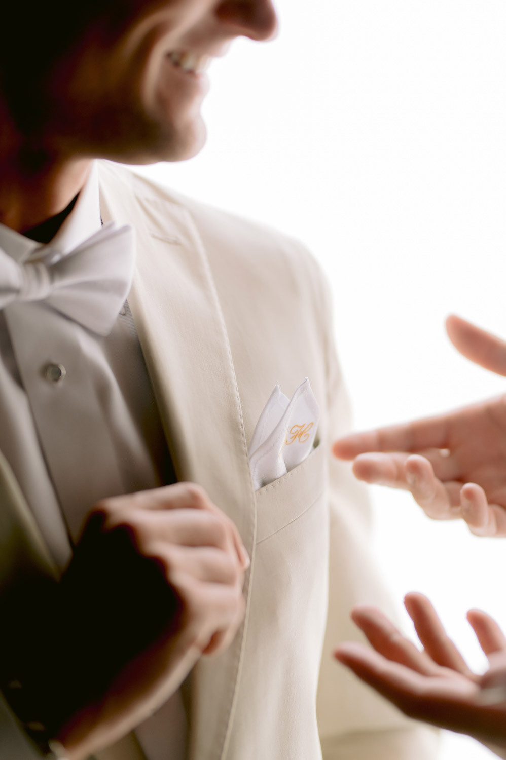 The groom shows his best friend the handkerchief in his jacket pocket. 