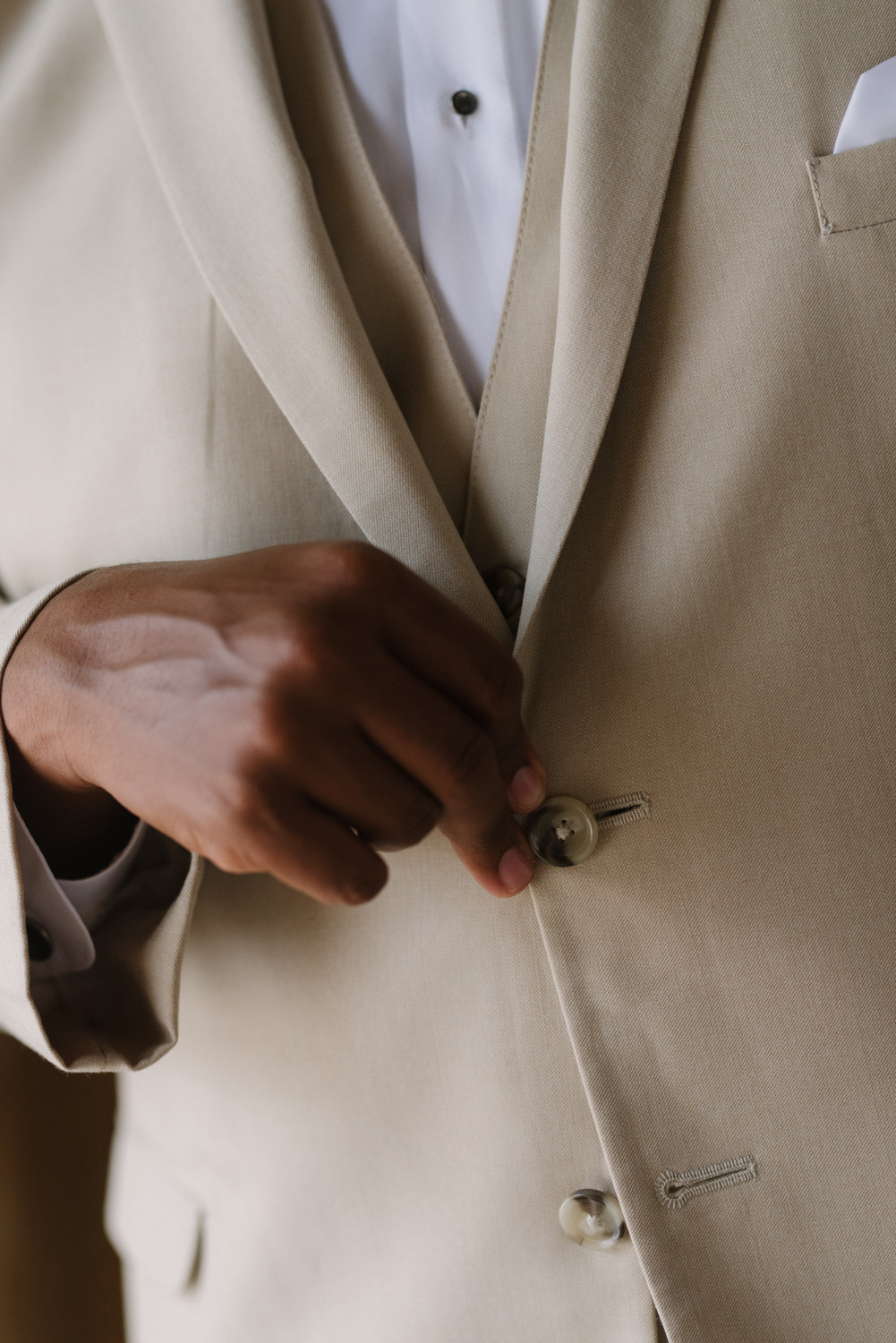 Жених застегивает пуговицы на пиджаке.