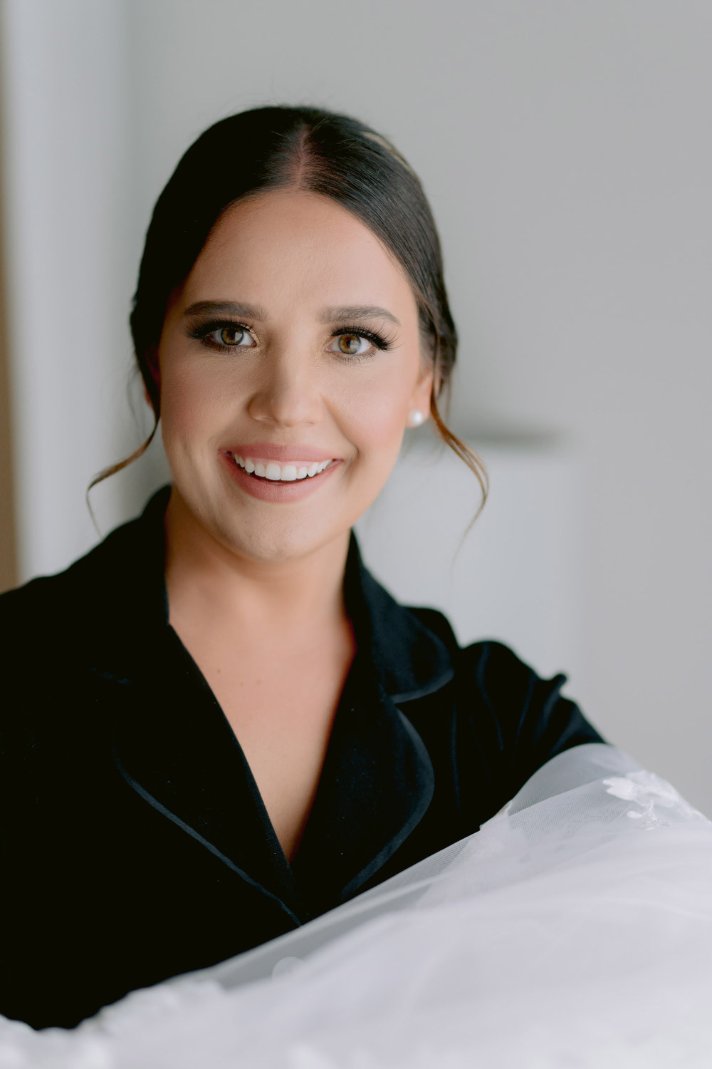The bride smiles at the photographer in the hotel room.