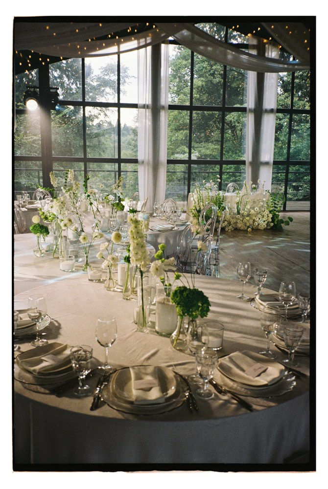 Reception table with florals by window during luxury wedding dinner